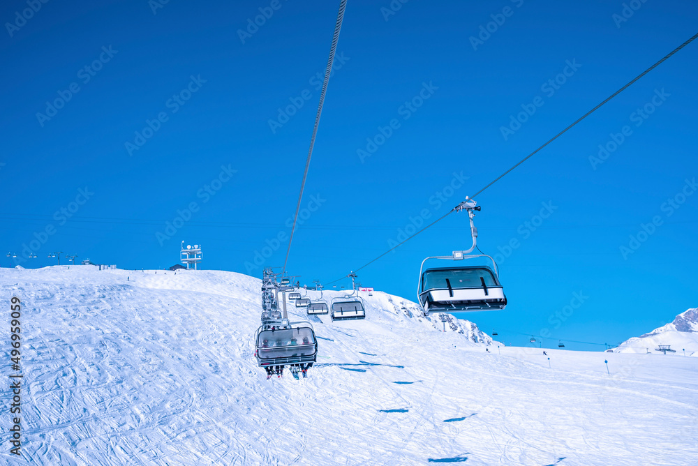 Ski lift moving over snow covered landscape against clear blue sky