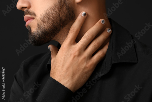 Canvas Print Man with stylish manicure touching his neck on black background, closeup