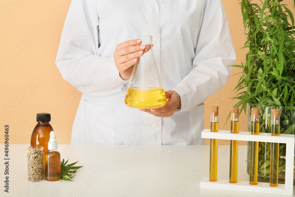 Female worker with flask of hemp oil in laboratory Female worker with flask of hemp oil in laboratory