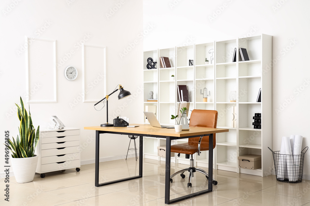 Modern workplace with laptop and lamp in interior of light office