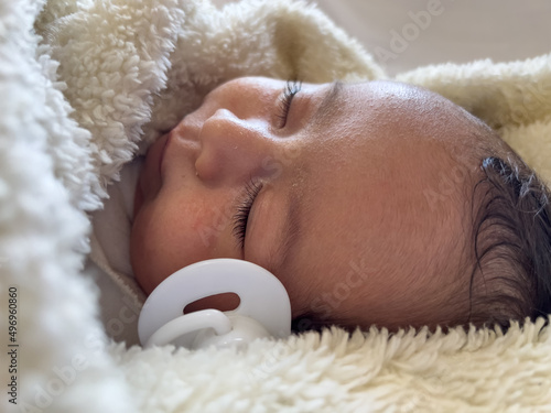 Sweet peaceful baby lying on a white bedsheet enjoy daytime nap photo