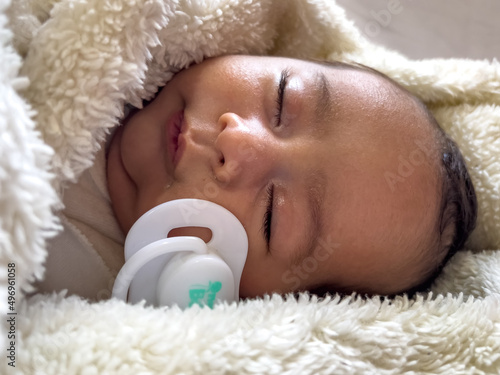 Sweet peaceful baby lying on a white bedsheet enjoy daytime nap photo