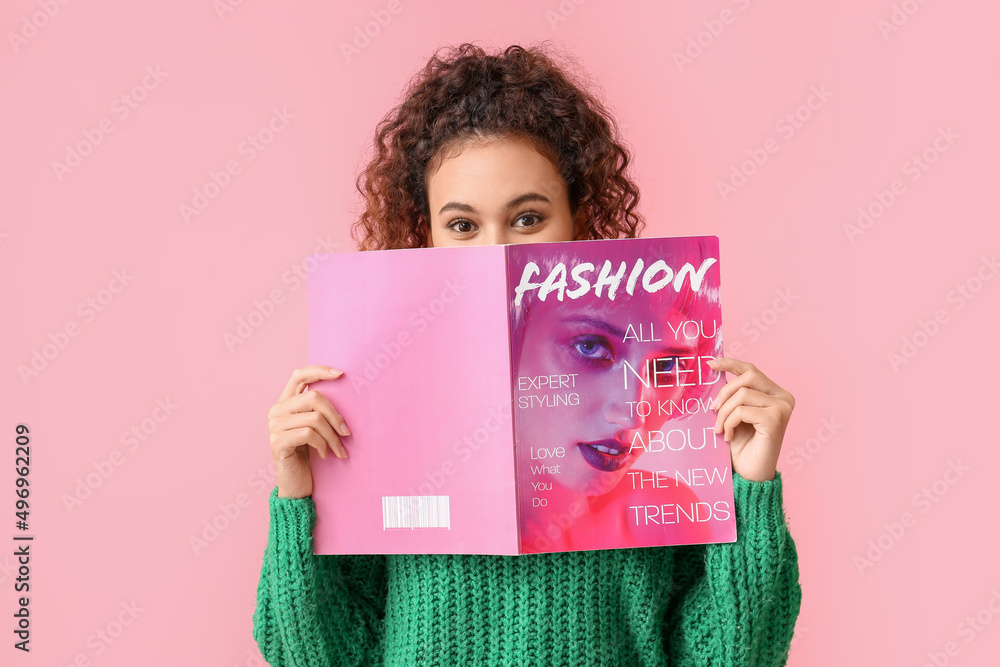 Young African-American woman in green sweater reading magazine on pink background - obrazy, fototapety, plakaty 
