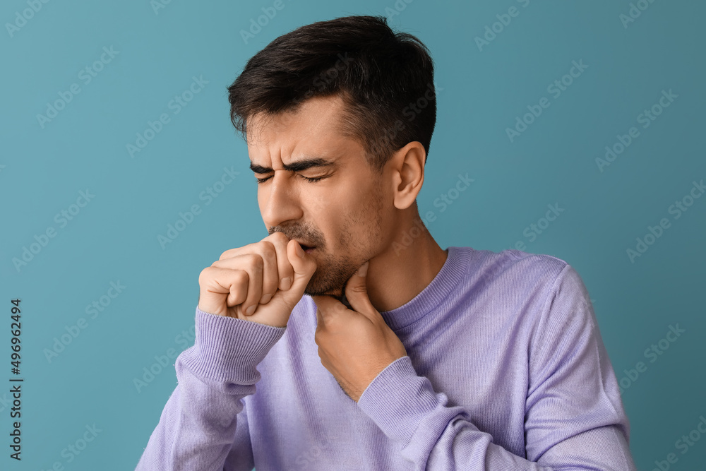 Ill young man with sore throat on blue background
