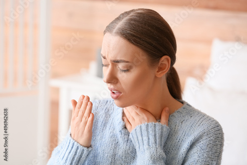 Fototapeta Naklejka Na Ścianę i Meble -  Ill coughing young woman with sore throat at home