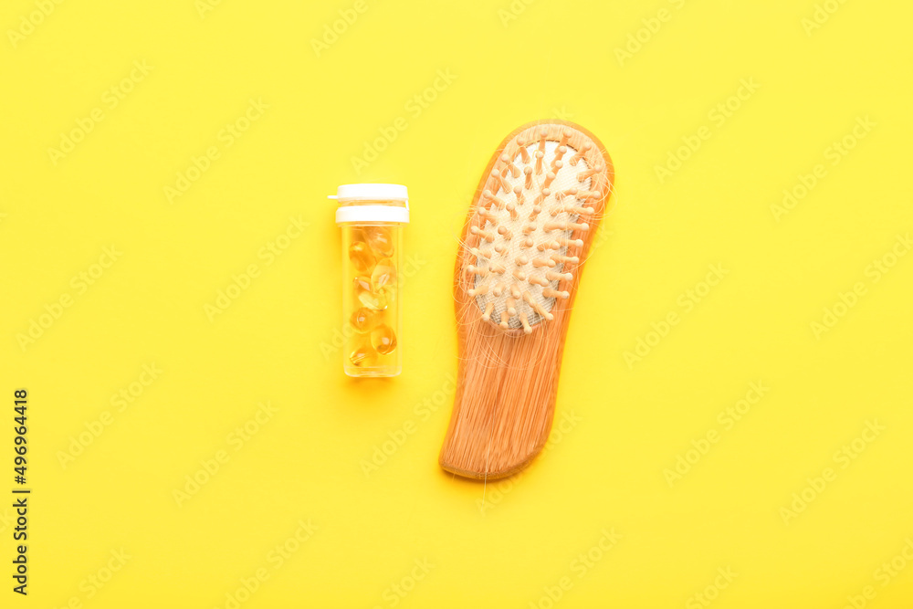 Brush with fallen down hair and pills on yellow background Brush with fallen down hair and pills on yellow background