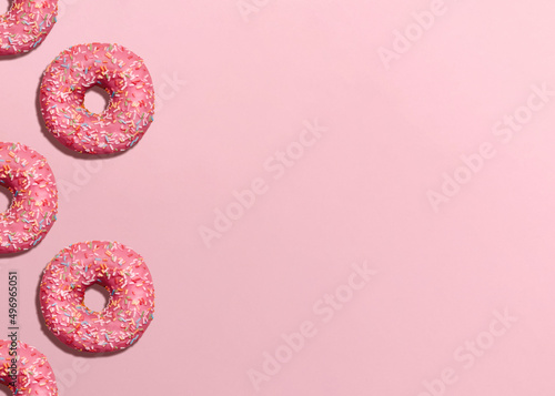 Donuts. Design template with copy space. Pink glazed doughnuts with sprinkles on pink background