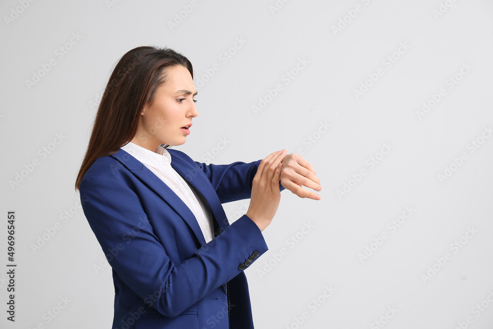 Portrait of stressed young secretary looking at watch on light background Portrait of stressed young secretary looking at watch on light background