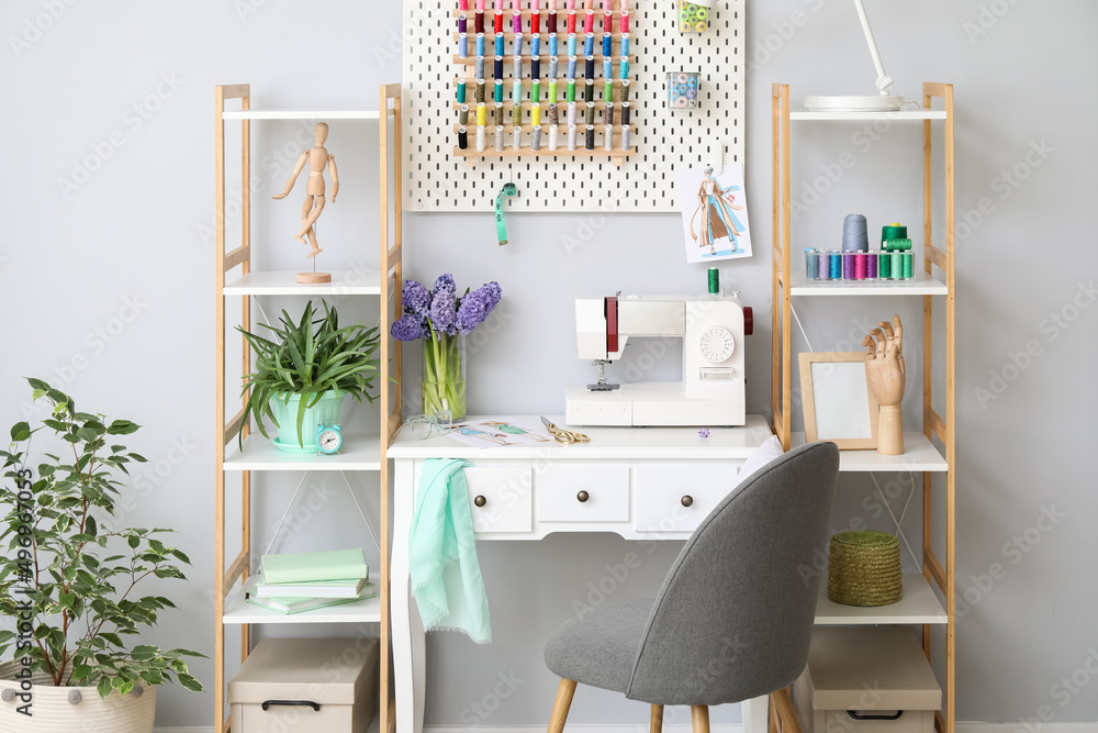 Interior of stylish atelier with tailor's workplace, shelving units and pegboard Interior of stylish atelier with tailor's workplace, shelving units and pegboard