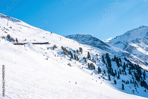 Ski trails on snow covered mountain. Scenic view of forest on white landscape against sky. Beautiful scenery during winter.