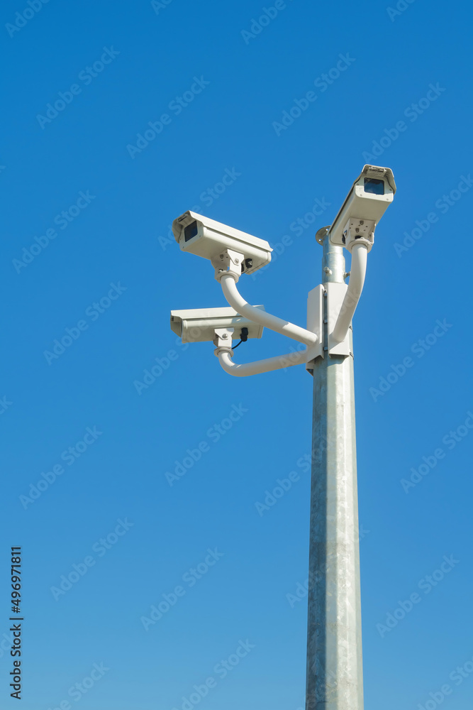 Three closed circuit television cameras against blue sky Three closed circuit television cameras against blue sky