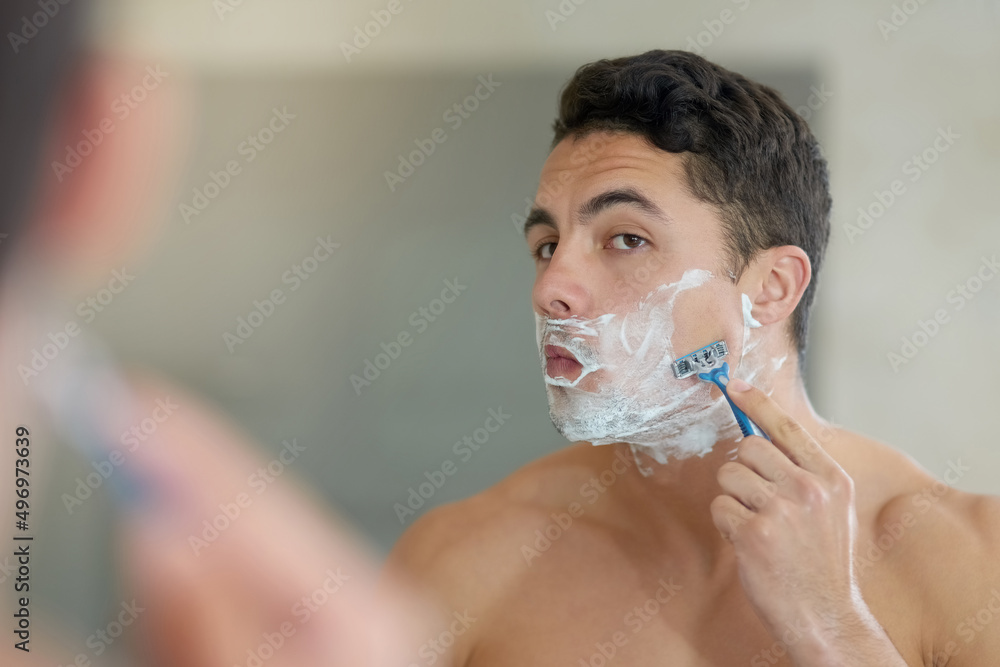 Easy does it.... Shot of a handsome young man shaving his facial hair in the bathroom.