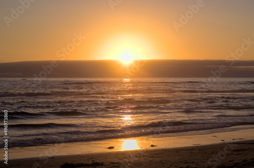 puesta de sol y ocaso en la orilla de playa con nubes en el horizonte y un peque  o bote