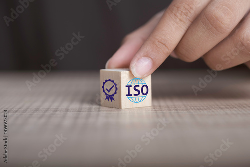 ISO quality control certification concept. Hand flip ISO smart globe icons with check mark guarantee icon on wooden cube and copy space.