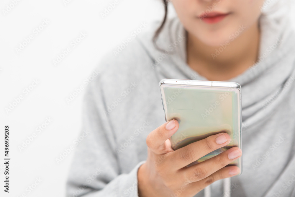 Beautiful Asian woman wearing grey casual shirt holding smartphone on white background and copy space. Cute Asian woman is smiling and chatting about something for social media concept Beautiful Asian woman wearing grey casual shirt holding smartphone on white background and copy space. Cute Asian woman is smiling and chatting about something for social media concept