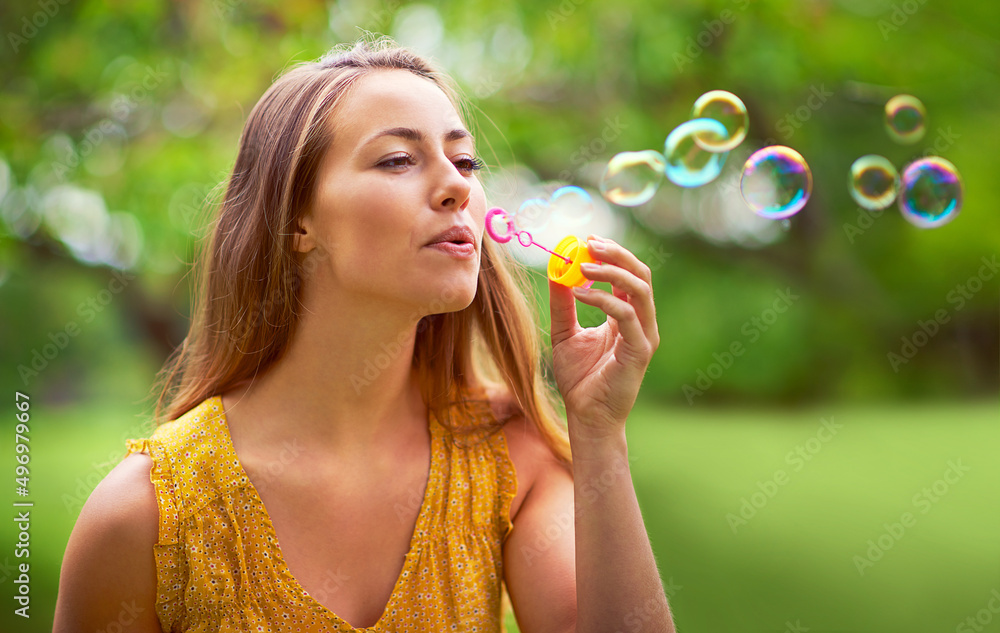 Feeling like a little girl again. Shot of a carefree young woman blowing bubbles in the park. Feeling like a little girl again. Shot of a carefree young woman blowing bubbles in the park.