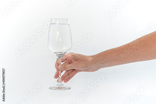 delicate hand holding the stem of a cup of water, white background