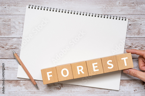 「FOREST」と書かれた積み木、ノート、ペン、手