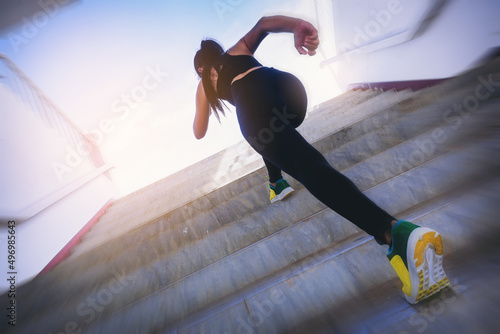Young woman running sprinting up stairs. Fit runner fitness runner during outdoor workout with speed zoom blurred. Selected focus