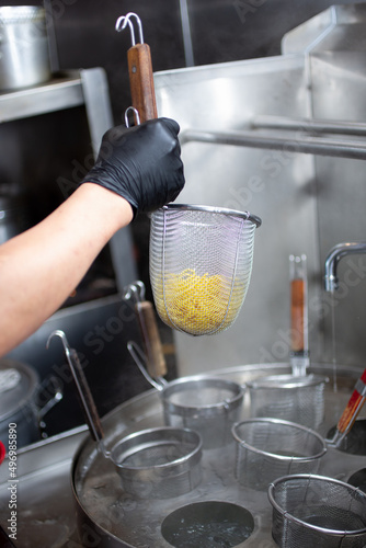 A view of a hand using a ramen noodle strainer.