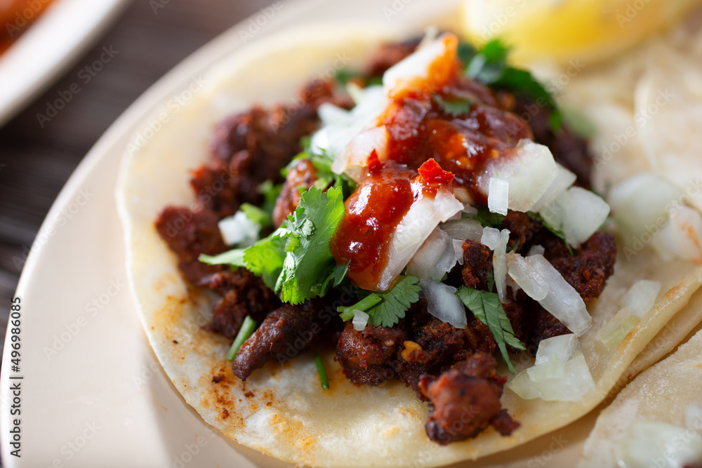 A closeup view of a plate of an al pastor street taco. A closeup view of a plate of an al pastor street taco.
