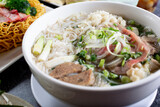 A view of a large bowl of pho with a variety of meat inside, in a restaurant or kitchen setting.