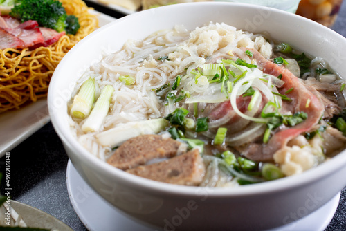 A view of a large bowl of pho with a variety of meat inside, in a restaurant or kitchen setting.