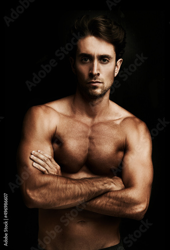 Hello ladies. Portrait of a well-built young man isolated on black with his arms crossed.