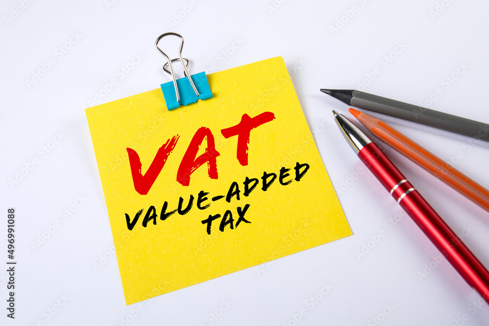 VAT. Value-added Tax. Sheet of note paper with text and a pen on a white table VAT. Value-added Tax. Sheet of note paper with text and a pen on a white table