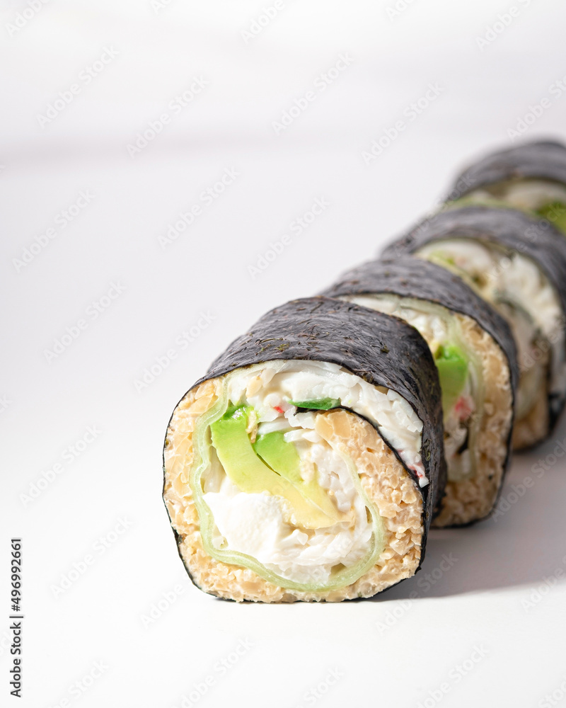 Sushi maki roll on white background. Macro close up of low-carb California KETO sushi with cauliflower rice, crab, avocado. Ketogenic diet. Japanese cuisine restaurant menu. Vertical, selective focus