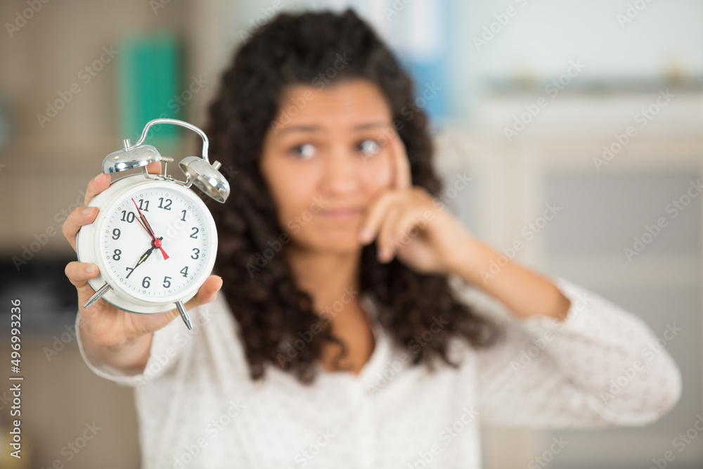 picture of woman holding alarm clock and thinking picture of woman holding alarm clock and thinking