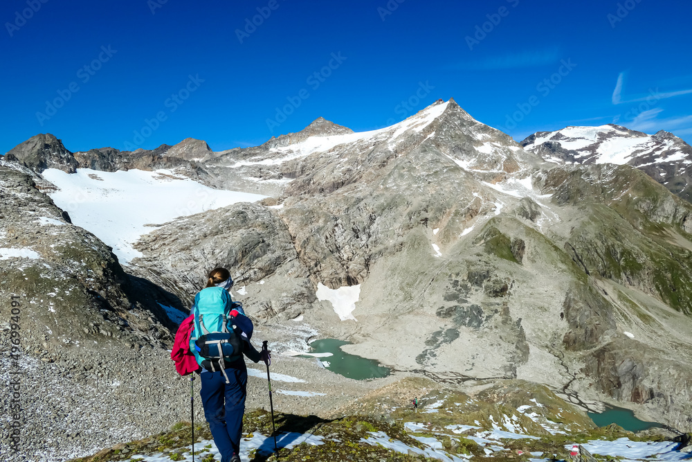 Hiking woman with scenic view on Hoher Sonnblick in High Tauern mountains in Carinthia, Salzburg, Austria, Europe, Alps. Glacier lakes of Goldbergkees in Hohe Tauern National Park. Freedom concept