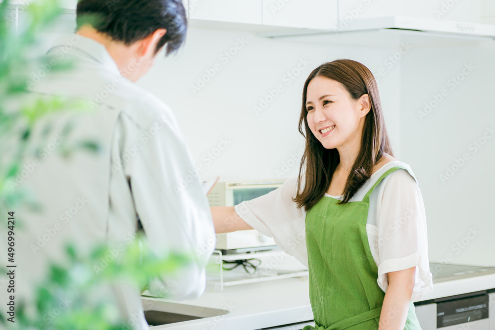 Fototapeta premium キッチンで話す作業着姿の男性と女性（水道・笑顔） 