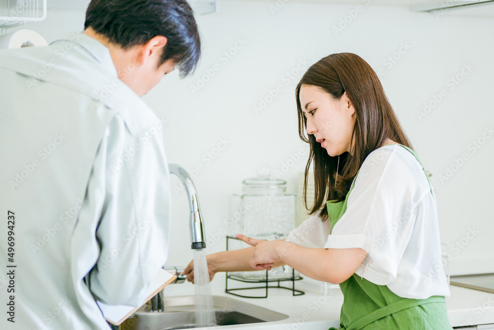 Obraz premium キッチンで話す作業着姿の男性と女性（水道・クレーム） 