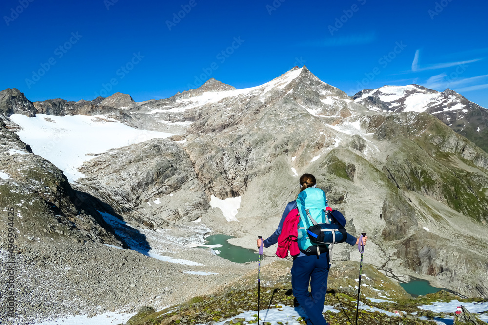 Hiking woman with scenic view on Hoher Sonnblick in High Tauern mountains in Carinthia, Salzburg, Austria, Europe, Alps. Glacier lakes of Goldbergkees in Hohe Tauern National Park. Freedom concept