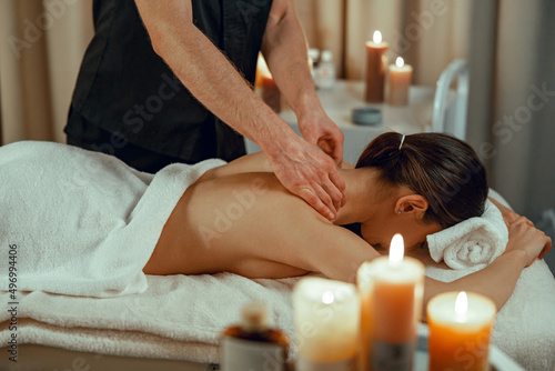 Professional masseur man doing back massage for female client at spa center. Relaxation, therapy.