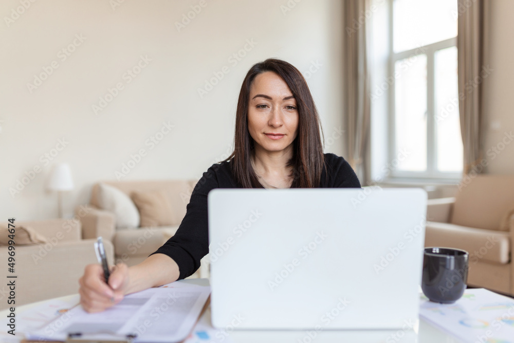 Asian woman working on laptop computer, smiling. Woman Working From Home On Laptop In Modern Apartment. Trendy woman working on laptop from home Asian woman working on laptop computer, smiling. Woman Working From Home On Laptop In Modern Apartment. Trendy woman working on laptop from home