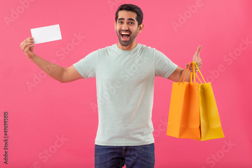 Happy young man with shopping bags and discount coupon in hands