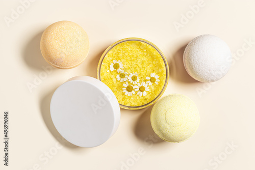 Bath salt sea and bath bomb with herbal extract of chamomile, sea salt crystals in jar, neutral beige spa background. Close up body care cosmetics, natural organic product, herbal medicine photo