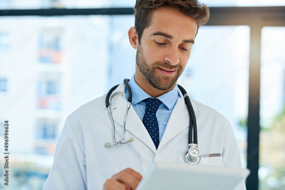 Getting a second opinion online. Shot of a busy doctor checking a patients medical records on his tablet. Getting a second opinion online. Shot of a busy doctor checking a patients medical records on his tablet.