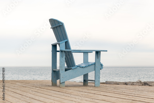 An Adirondack  or Muskoka  chair sits on a simple wooden deck in spring.  Side rear view. Shot in Toronto s iconic Beaches neighbourhood in early spring.