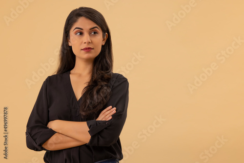 Portrait of a young woman looking elsewhere with arms crossed