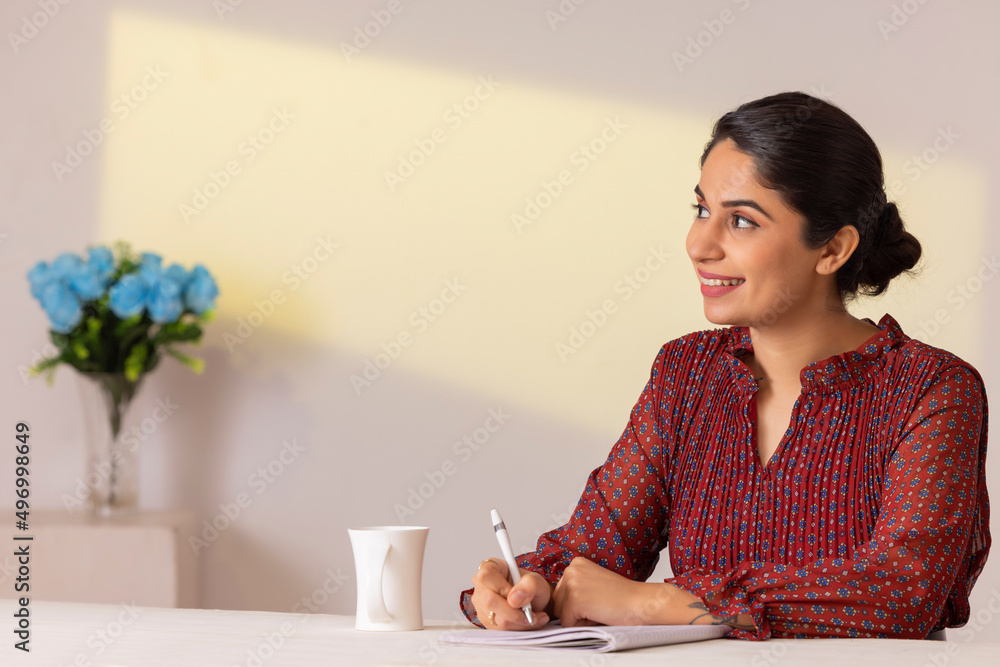 Portrait of a young woman executive taking notes on notebook at her desk in office Portrait of a young woman executive taking notes on notebook at her desk in office