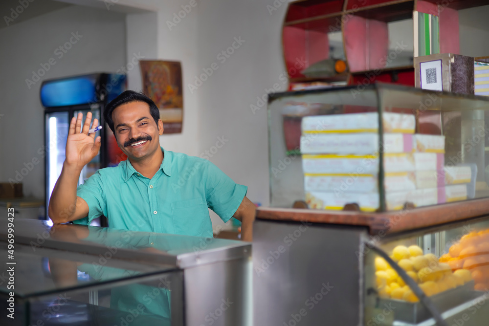 Fototapeta premium Portrait of happy Sweet shop owner standing at counter