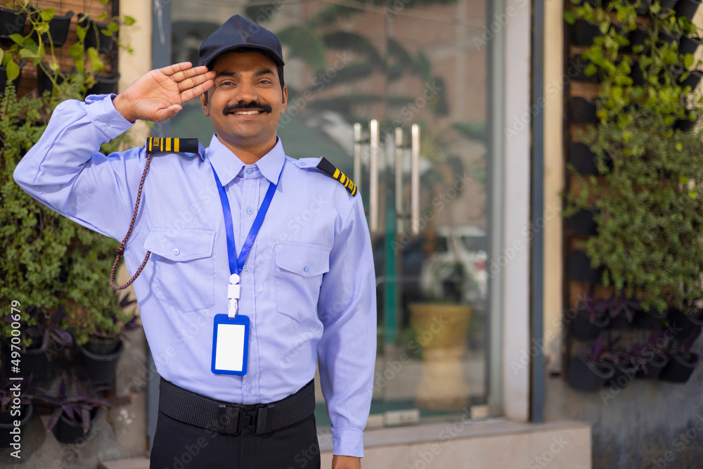 Portrait of security guard saluting while working at gate Stock Photo