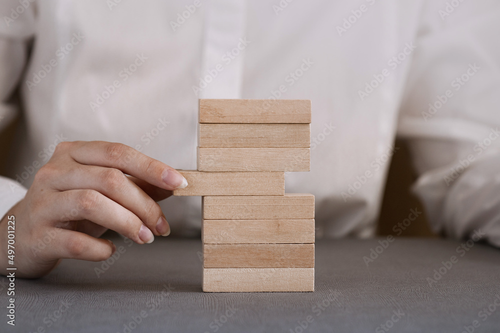 Close-up hand takes one block on a wooden block tower. Close-up hand takes one block on a wooden block tower.