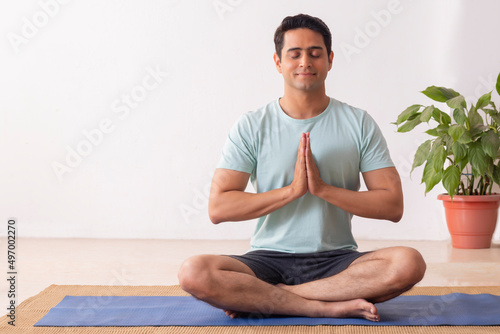 Portrait of a young man meditating at home photo