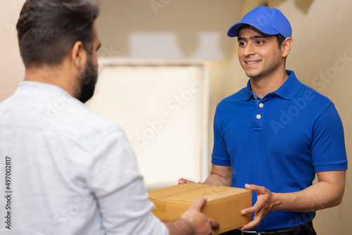Portrait of a courier delivery boy delivering parcel to customer