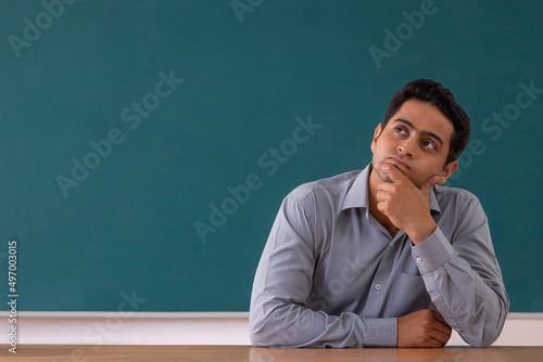 Photography Portrait of a school teacher thinking with hand on chin while sitting classroom
