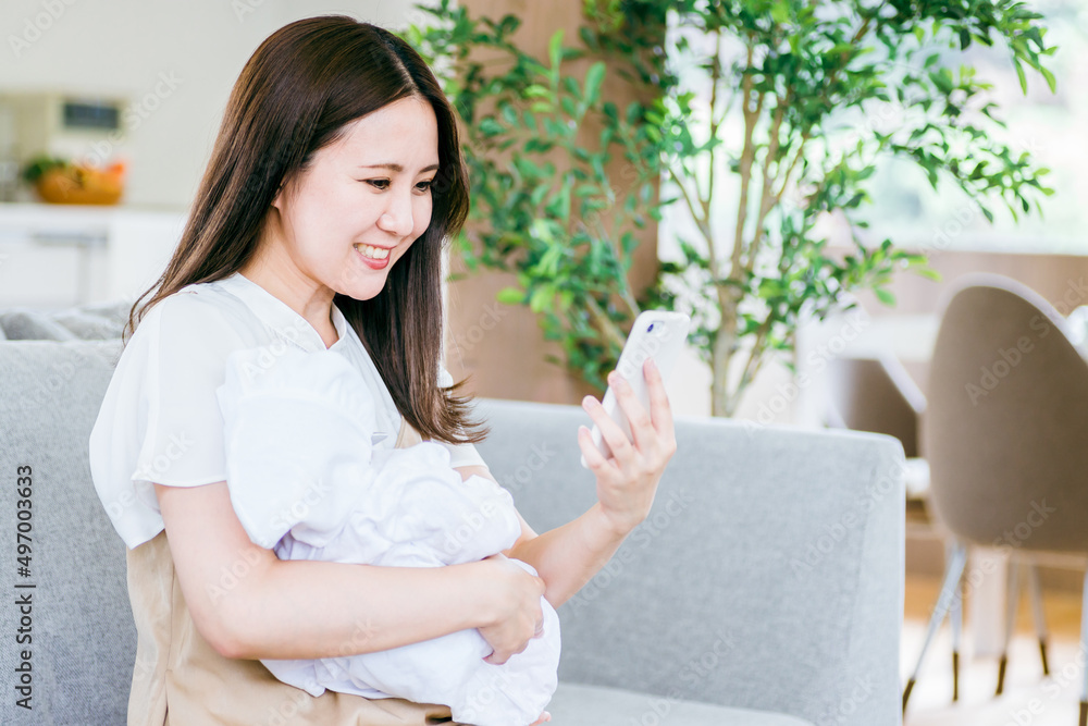 赤ちゃんを抱きながらスマホを使う女性
赤ちゃんを抱きながらスマホを使う女性